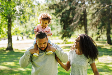 Happy boy and his parents walking in the park on a sunny day