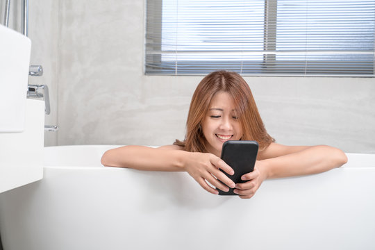 Young And Beautiful Girl Using Phone Relaxing In The Retro Bath Indoors