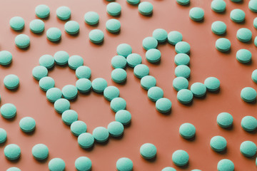 Vitamins B 12 in the shape of a heart on a red substrate, poured out of a white jar.