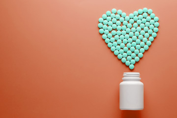 Vitamins B 12 on a red heart-shaped substrate, poured out of a white jar.