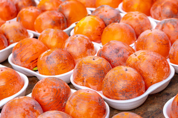 Rows of fresh ripe persimmon for sale in a street market