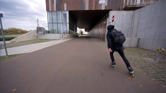 Man skating with backpack on inline skates with three wheels in slow motion