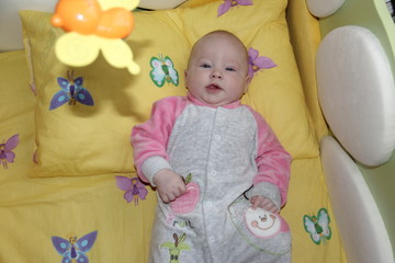 the baby is lying in a yellow crib