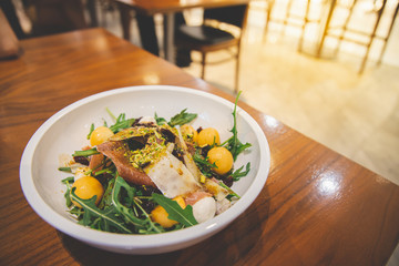 Fresh crispy salad bacon, cantaloupe with a green vegetable on a plate, on a wooden table.