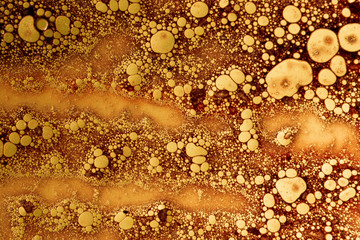 abstract background with rusty colored oil bubbles on water with soap foam