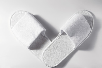 Top view of white slippers on a white wooden background. Pair of blank hotel footwear