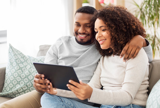 Technology, Internet And People Concept - Happy African American Couple With Tablet Computer At Home