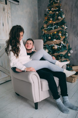 Obraz premium A guy with a girl is celebrating Christmas. A loving couple enjoys each other on New Year's Eve in a cozy home environment. New Year's love story.