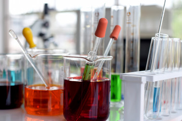 glass test tubes and flasks with colorful liquid on blue background with molecular structure