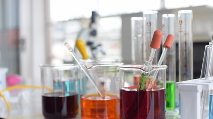 glass test tubes and flasks with colorful liquid on blue background with molecular structure