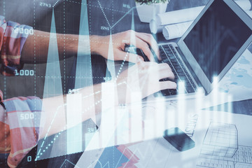 Double exposure of stock graph with businessman typing on computer in office on background. Concept of hard work.