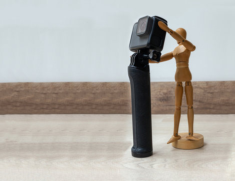 Wooden dummy with a photo and video camera on a wooden floor and white background