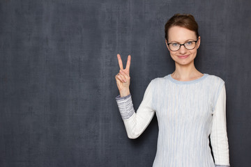 Portrait of happy young with glasses, showing peace gesture