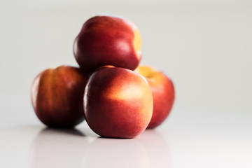 Fototapeta na wymiar Ripe red nectarines, peaches, apples on a white table. Tasty bright fruits. Isolated object.