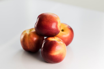 Ripe red nectarines, peaches, apples on a white table. Tasty bright fruits. Isolated object.