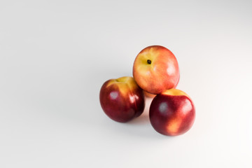 Ripe red nectarines, peaches, apples on a white table. Tasty bright fruits. Isolated object.