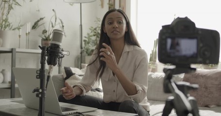 Young adult female influencer recording vlog at home with camera