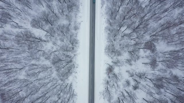 Top view of traffic on a road surrounded by winter forest