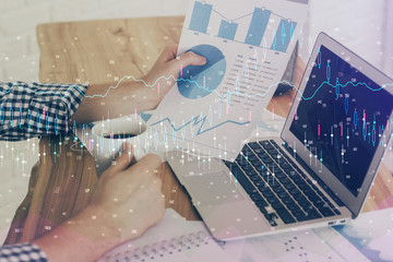 Double exposure of man's hands writing notes of stock market with forex chart.