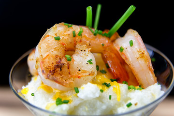 Close view of a shrimp and grits appetizer in a martini glass. 