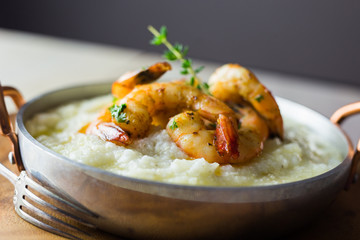 Shrimp and grits in a copper handled dish.  Copy space. 