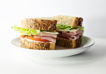 Ham sandwich on wheat bread with tomato, mayonnaise and lettuce, cut in half. 