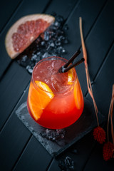 Grapefruit cocktail with Gin or vodka in a clear glass with ice on a black wooden background. Refreshing citrus lemonade, summer refreshing drink