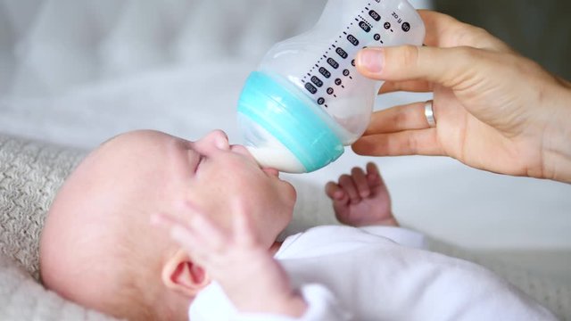 Mother Hand Feeding Her Baby. Infant Formula And Bottle Feeding Concept.