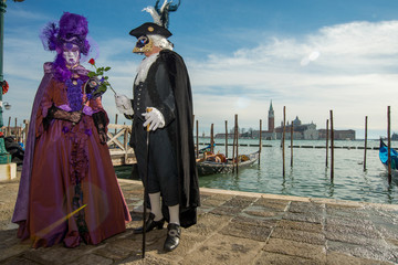 Obraz premium Couple homme et femme costumé de noir et de violet devant le grand canal au carnaval di Venise en Italie 
