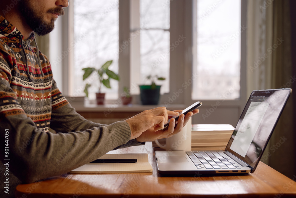 Wall mural freelancer is making actions in smartphone while working at home.