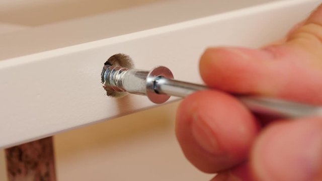 Installation and assembling furniture at home. Male hand with allen key hexagonal tool screwing furniture screw into wooden plank. Do it yourself furniture assembly