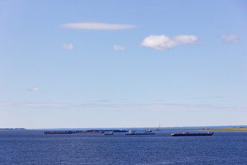 A large cargo ships and barges at sea on the horizon