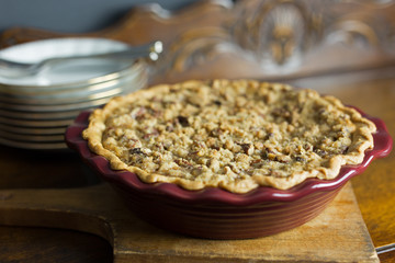 Whole peach pie with streusel topping on a vintage buffet. 