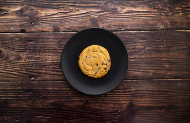 Obraz na płótnie Canvas Overhead view of cookie on black plate. Freshly baked and delicious a cookie on rustic wooden background.