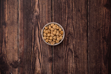 Obraz na płótnie Canvas Overhead view of roasted hazelnuts in a bowl on rustic wood background.
