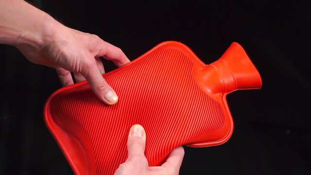Red rubber hot-water bottle in the patients hands.