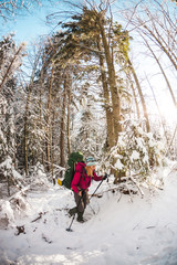 Woman with backpack and snowshoes in the winter mountains.