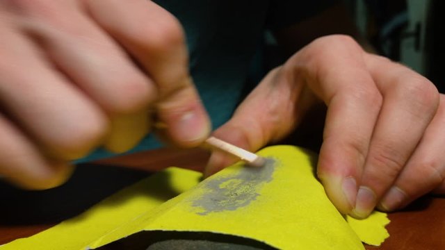 Man rubs a soldering copper tip on sandpaper. Close up