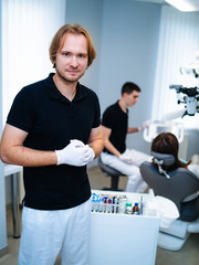 A portrait of a dentist with his team working in the background. Oral care concept.
