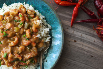 Crawfish etouffee over rice, shown with whole crawfish or crayfish on a rustic table. Copy space. 