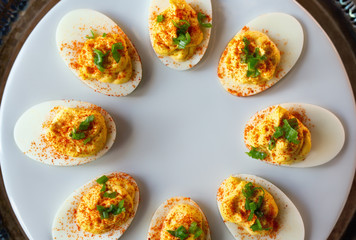 Overhead view of several deviled eggs with paprika and scallions. 