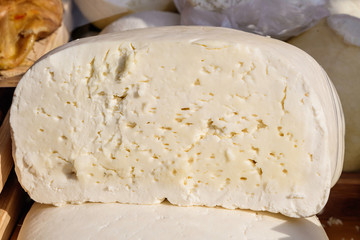 A piece of home made cheese from cow and sheep milk, known as telemea, displayed for sale at a street food market, side view of healthy food photographed with soft focus