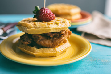 Close up view of chicken and waffles with a strawberry garnish. 