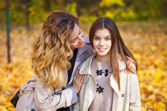 Happy mother and daughter are walking in the autumn park