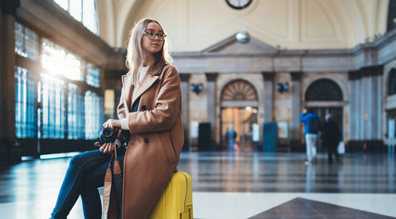 Tourist photographer woman with suitcase on platform station in Barcelona. Girl traveler waiting train enjoy holiday weekend vacation in transport railway. Travel railroad station concept