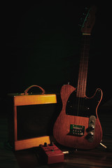 Electro ukulele with effect pedal and amplifier standing in the dark room dramatically lightning...