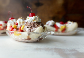 Two banana splits in glass ice cream boats with fruit topping. 