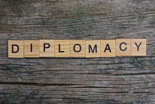 word diplomacy made of brown wooden letters on a gray table