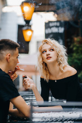 Stylish girl holds a lighter in her hand near her smoking boyfriend.  The inscription on the plate 