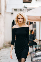 Sexy girl in a black dress walking down the street